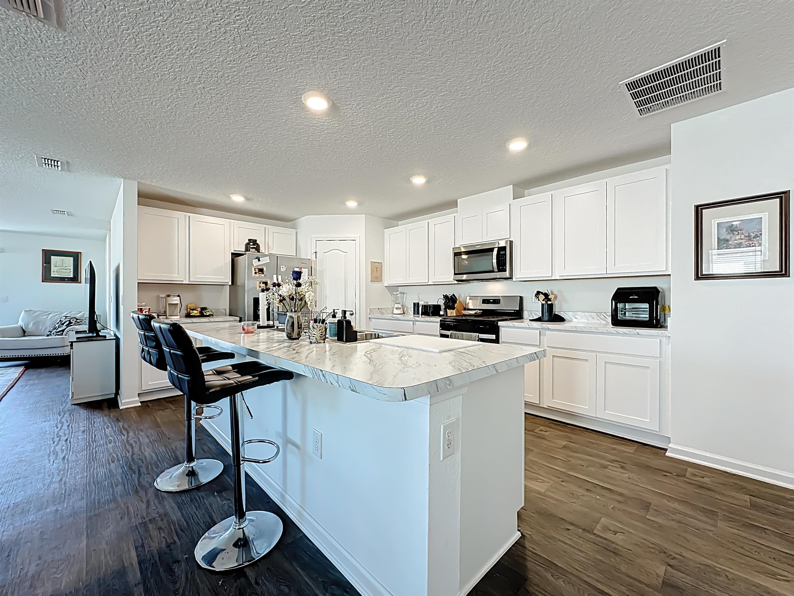 16 Encanto Way Street St. Augustine, FL 32084 - Photo 13 of 56 Kitchen featuring light countertops, a textured ceiling, stainless steel appliances, white cabinets, and dark wood finished floors