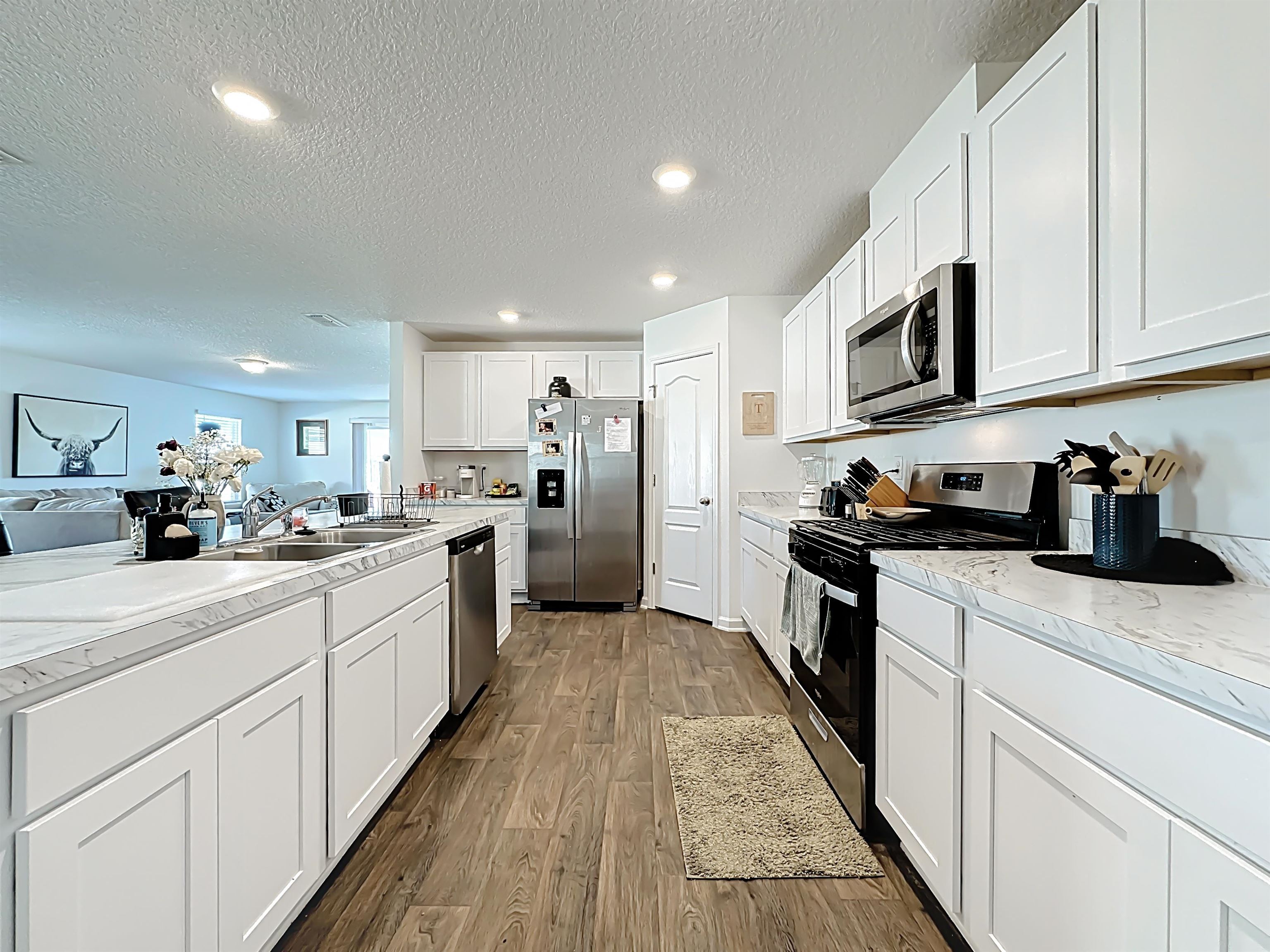 16 Encanto Way Street St. Augustine, FL 32084 - Photo 14 of 56 Kitchen with stainless steel appliances, white cabinets, a textured ceiling, dark wood-style flooring, and recessed lighting
