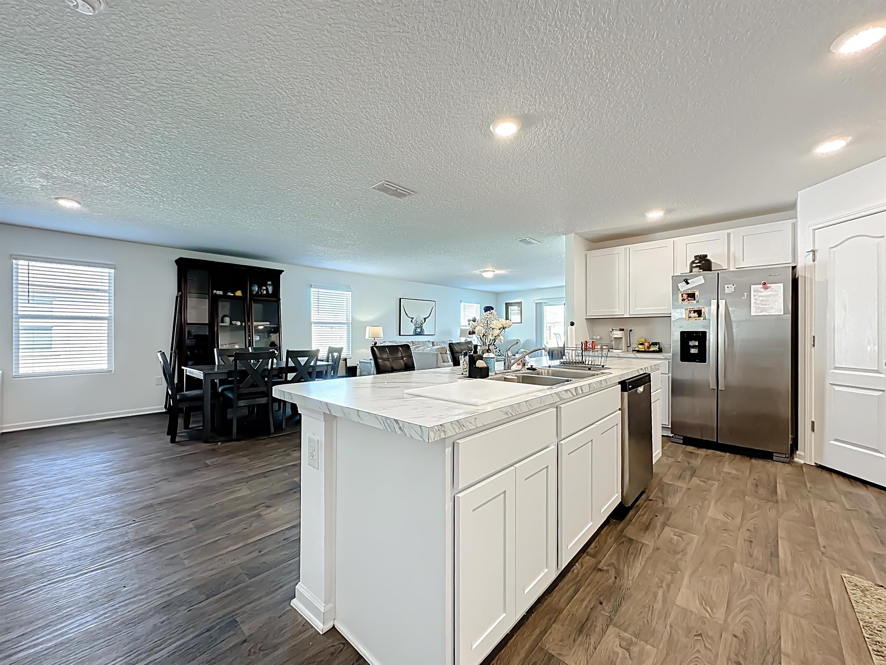 16 Encanto Way Street St. Augustine, FL 32084 - Photo 54 of 56 Kitchen with light countertops, white cabinets, stainless steel appliances, open floor plan, and a textured ceiling