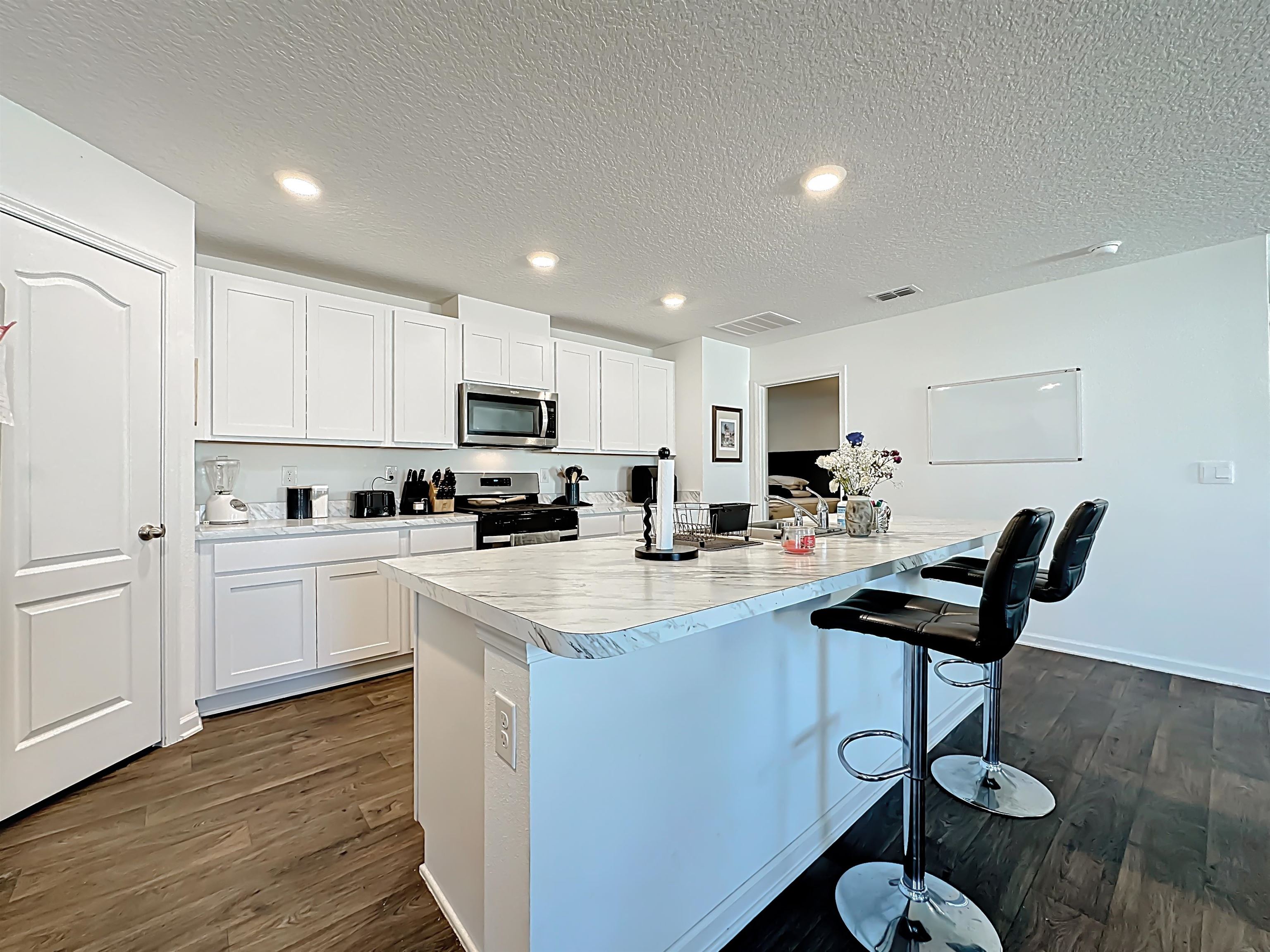 16 Encanto Way Street St. Augustine, FL 32084 - Photo 16 of 56 Kitchen with light countertops, white cabinetry, a breakfast bar area, stainless steel appliances, and a textured ceiling
