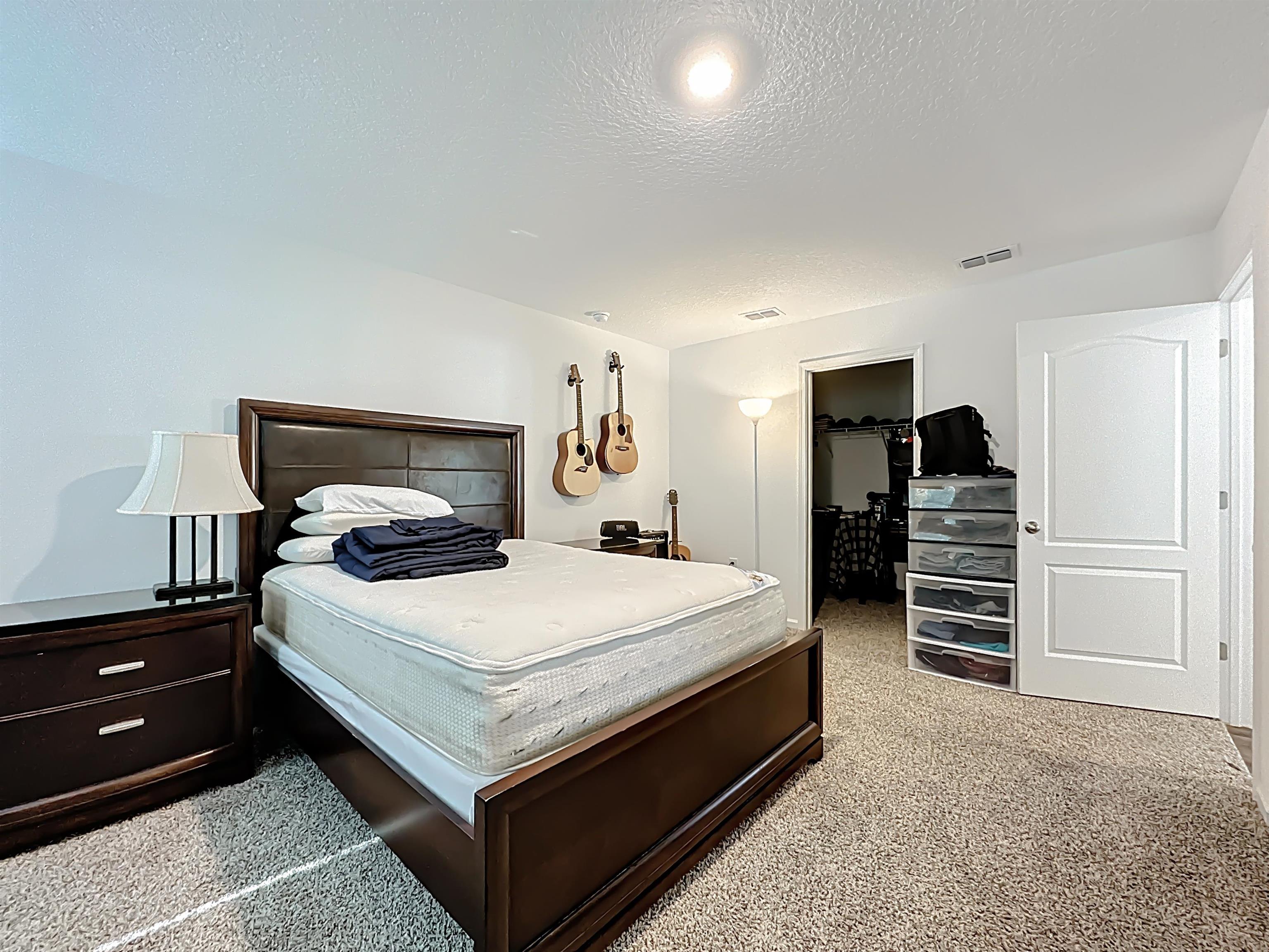 16 Encanto Way Street St. Augustine, FL 32084 - Photo 22 of 56 Carpeted bedroom featuring a walk in closet and a textured ceiling