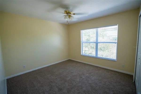 an empty room with a window and a ceiling fan