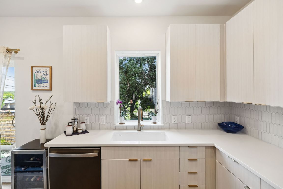 4802 South Congress Avenue, Unit 215 Austin, TX 78745 - Photo 8 of 32 Kitchen with stainless steel dishwasher, backsplash, light countertops, light brown cabinets, and modern cabinets