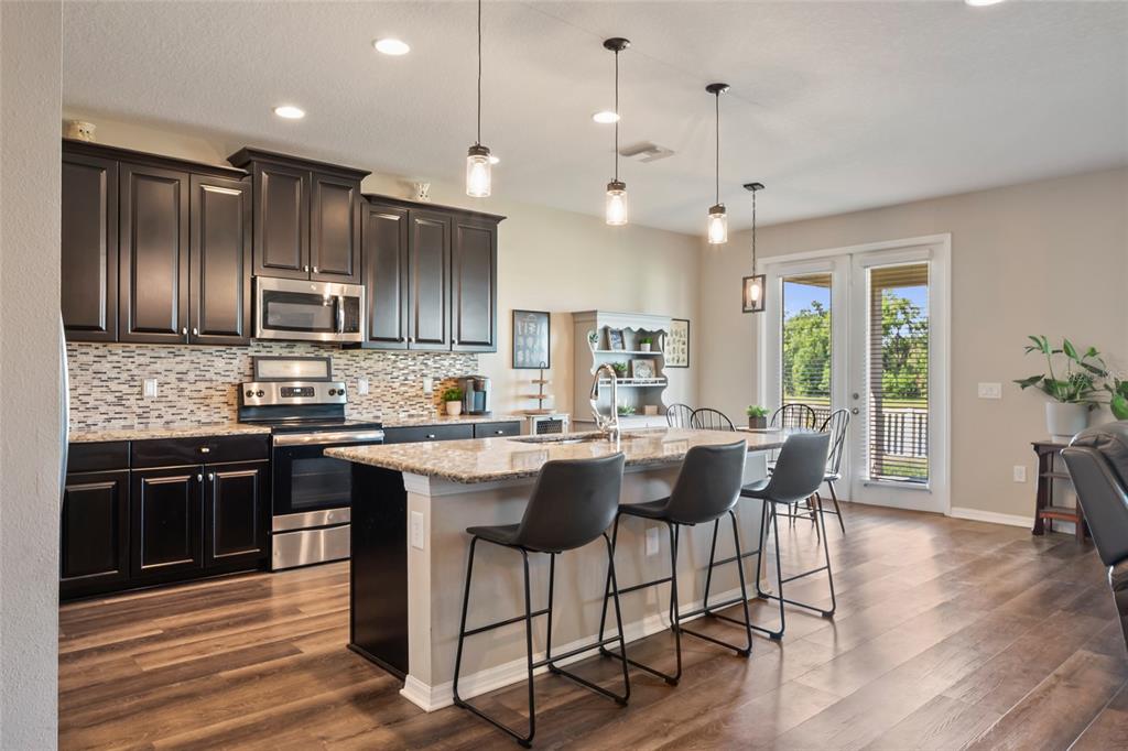 18428 Malinche Loop Spring Hill, FL 34610 - Photo 13 of 62 a kitchen with kitchen island granite countertop wooden floors and white cabinets