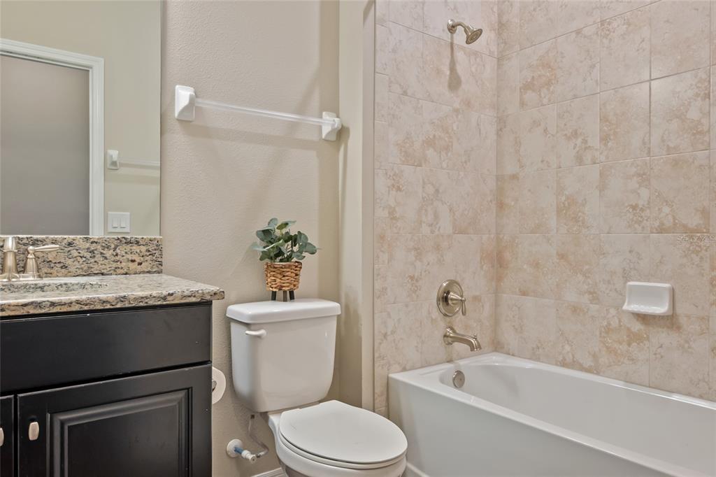 18428 Malinche Loop Spring Hill, FL 34610 - Photo 31 of 62 a bathroom with a granite countertop sink a toilet a mirror and bathtub