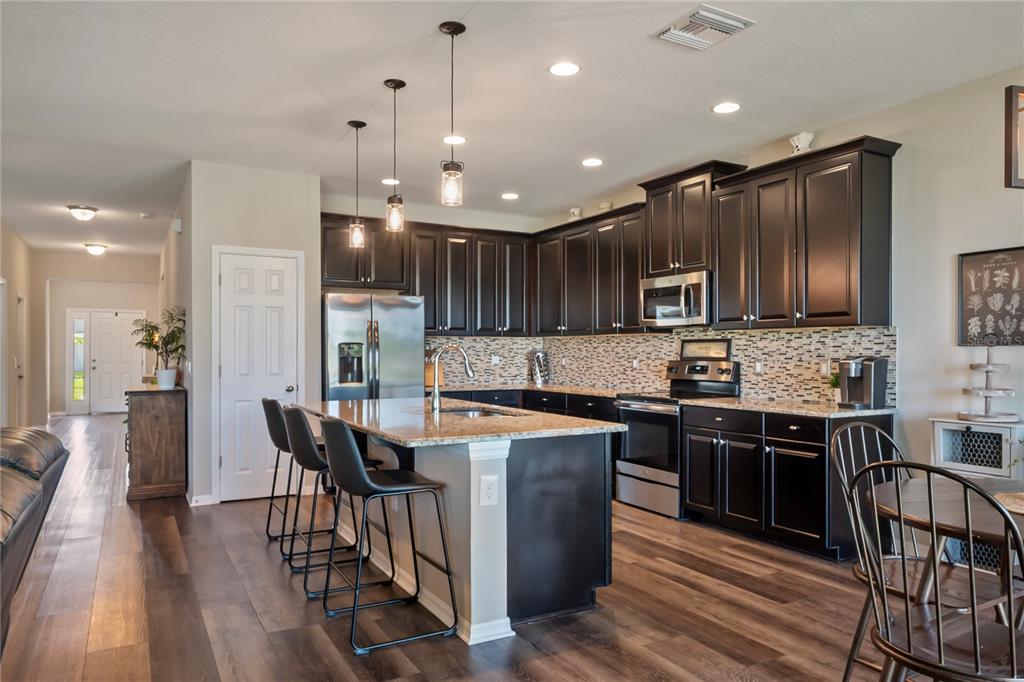 18428 Malinche Loop Spring Hill, FL 34610 - Photo 8 of 62 a kitchen with stainless steel appliances kitchen island granite countertop a stove a sink a microwave a center island and a refrigerator