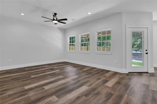 a view of empty room with wooden floor and fan