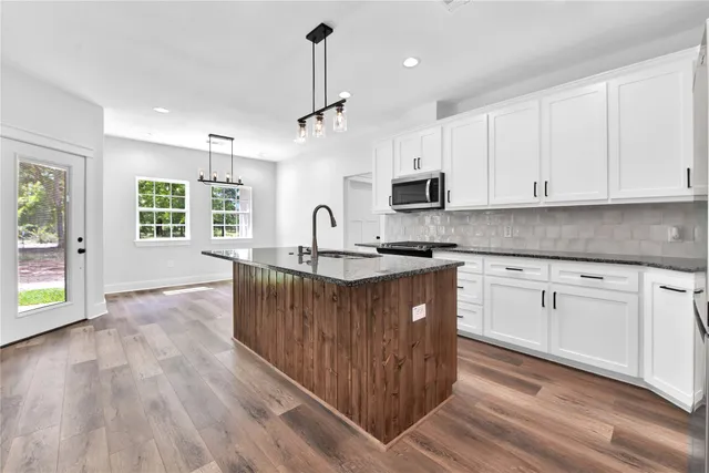 a kitchen with stainless steel appliances granite countertop a stove a sink dishwasher and a refrigerator with wooden floor