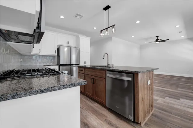 a kitchen with stainless steel appliances granite countertop a sink a stove and a refrigerator