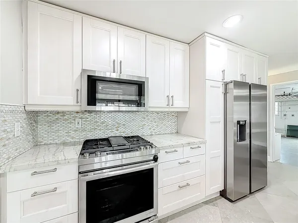a kitchen with granite countertop white cabinets and white stainless steel appliances