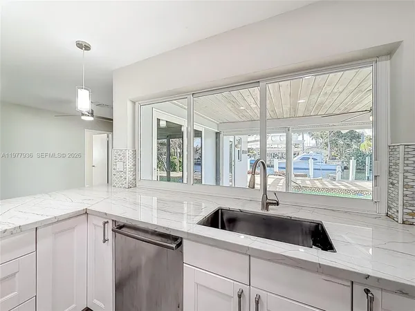 a kitchen with granite countertop stainless steel appliances white cabinets and a sink