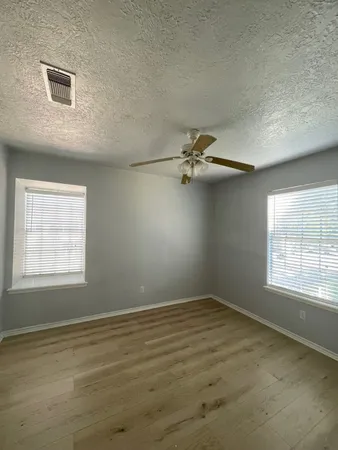 a view of empty room with wooden floor and fan