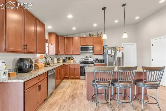 a kitchen with stainless steel appliances granite countertop wooden cabinets refrigerator dining table and chairs