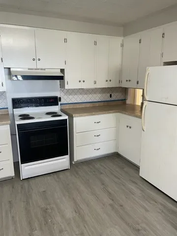 a kitchen with granite countertop white cabinets and white appliances