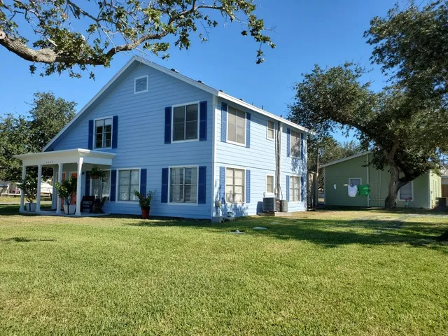a view of a yard in front of a brick house with a large tree