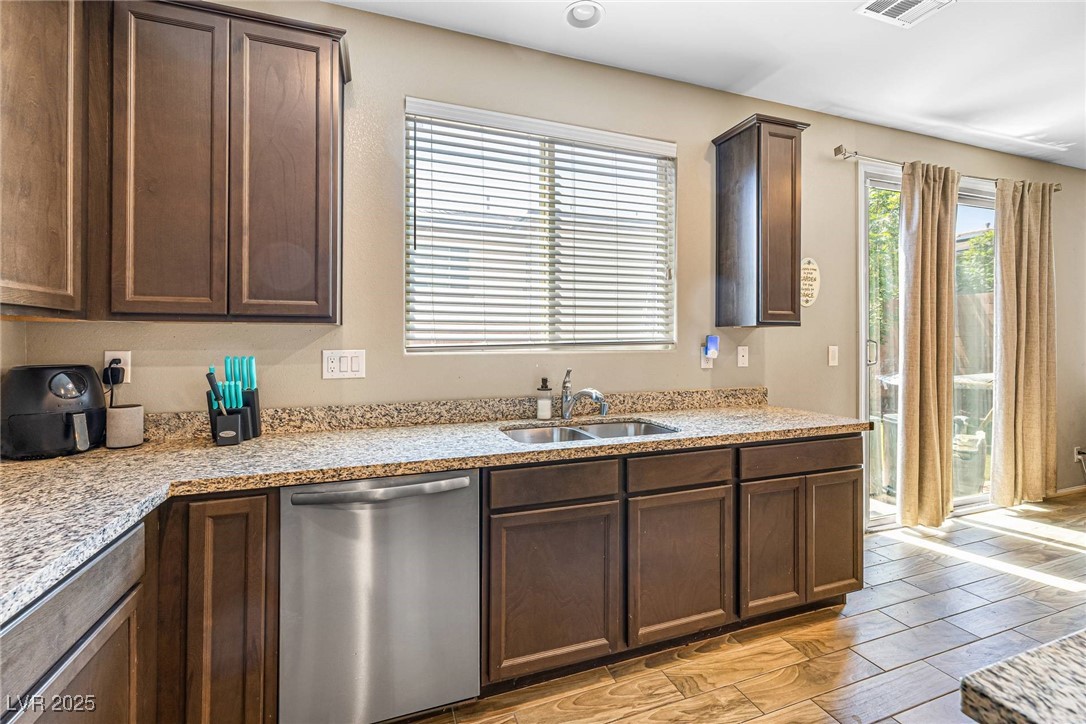 10523 Laurel Mountain Lane Las Vegas, NV 89166 - Photo 33 of 36 Kitchen featuring dishwasher, plenty of natural light, and dark brown cabinets