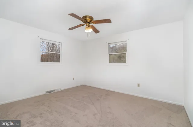 an empty room with closet and a chandelier fan