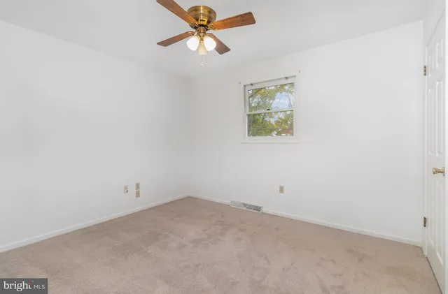 an empty room with a ceiling fan and carpet