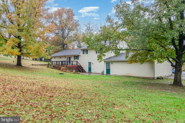 a view of a house with a yard and large trees