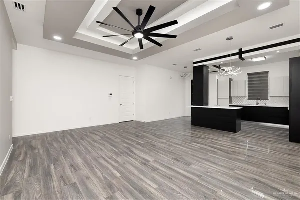 an empty room with wooden floor and a ceiling fan