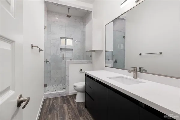 a bathroom with a sink a toilet a shower and a mirror