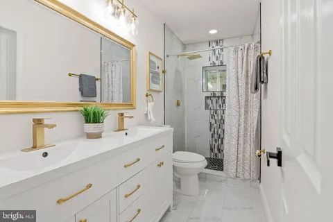 a bathroom with a shower sink vanity mirror and toilet