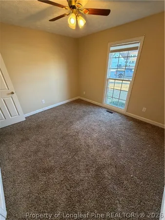 an empty room with windows and fan