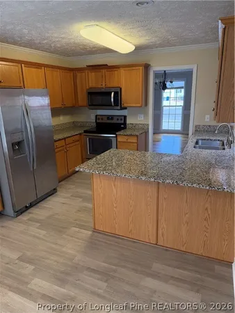 a kitchen with granite countertop a refrigerator cabinets and wooden floor