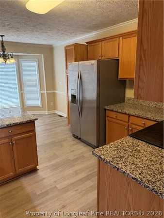 a kitchen with granite countertop a refrigerator and a stove top oven