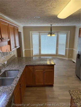 a kitchen with kitchen island granite countertop a sink a counter space and cabinets