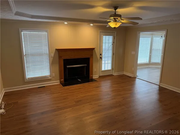 a view of an empty room with wooden floor fireplace and a window