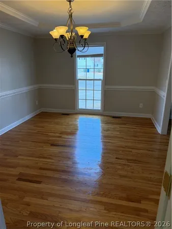 a view of empty room with wooden floor and window