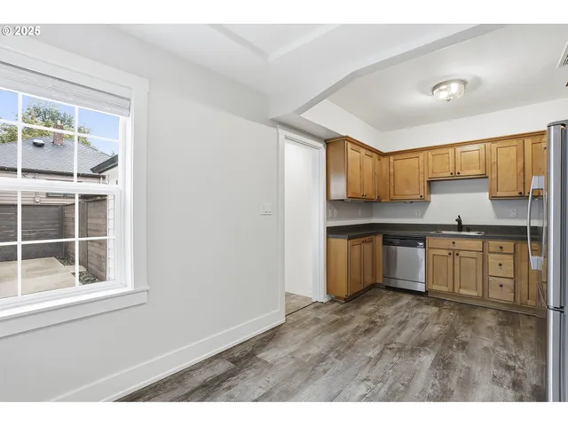 a kitchen with granite countertop a stove a sink wooden cabinets and a window