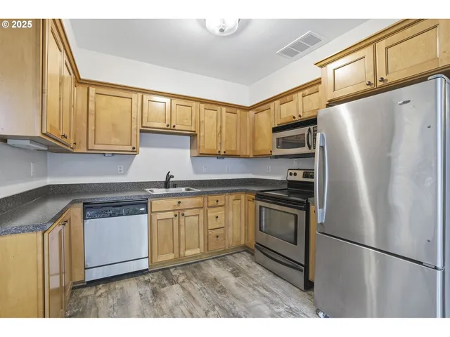 a kitchen with stainless steel appliances granite countertop a refrigerator a stove a sink and a microwave