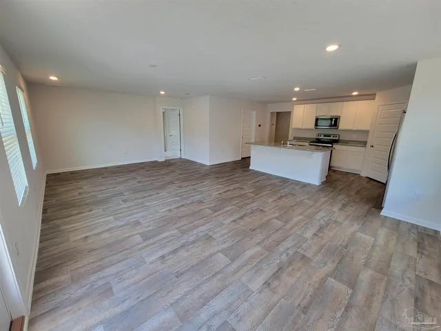 a view of kitchen with kitchen island wooden floors and stainless steel appliances