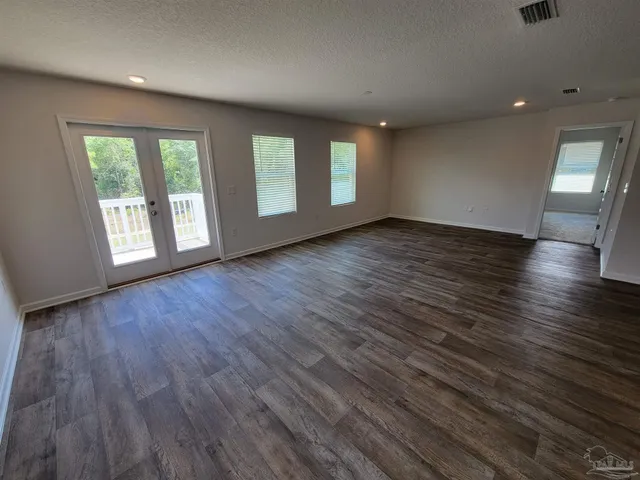 a view of an empty room with wooden floor and window