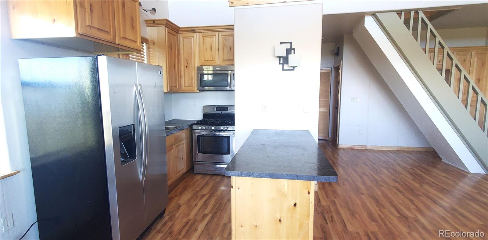4984 Edmond Road Fort Garland, CO 81133 - Photo 7 of 24 a kitchen with stainless steel appliances granite countertop a refrigerator a stove and a wooden floor