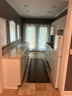 203 Indian Trail Road Seneca, SC 29672 - Photo 11 of 14 An efficient galley kitchen in lower level features stone countertops, tile flooring, and classic crown molding details.