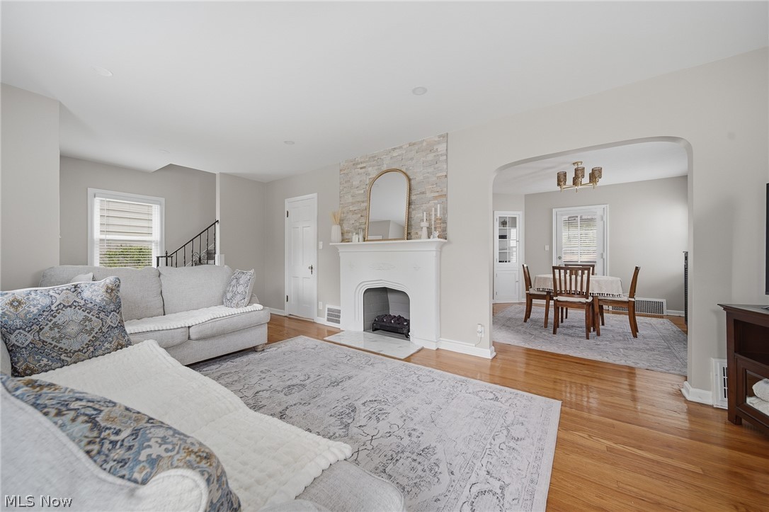 2231 Brockway Road University Heights, OH 44118 - Photo 7 of 46 Living room featuring hardwood flooring, a fireplace with a decorative mantel and stone surround, and an arched entryway to the dining area