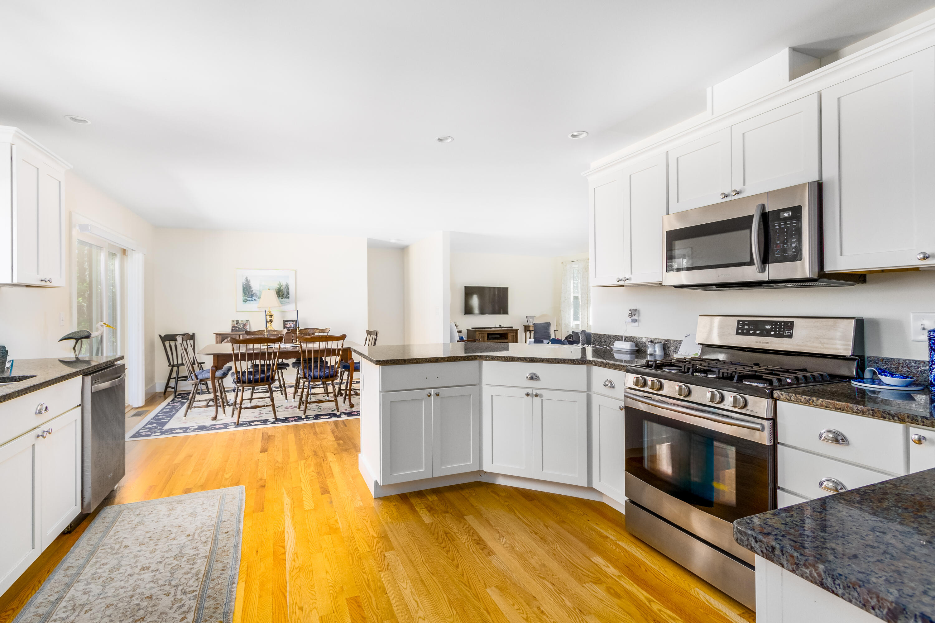40 Pine Needle Road Wellfleet, MA 02667 - Photo 15 of 36 a kitchen with stainless steel appliances granite countertop a stove top oven a sink dishwasher and white cabinets with wooden floor