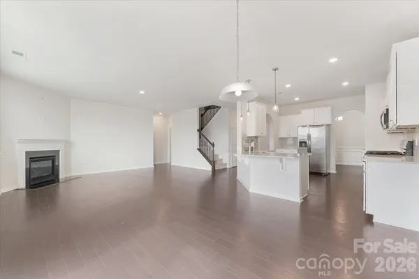 a view of empty room with kitchen view and a fireplace