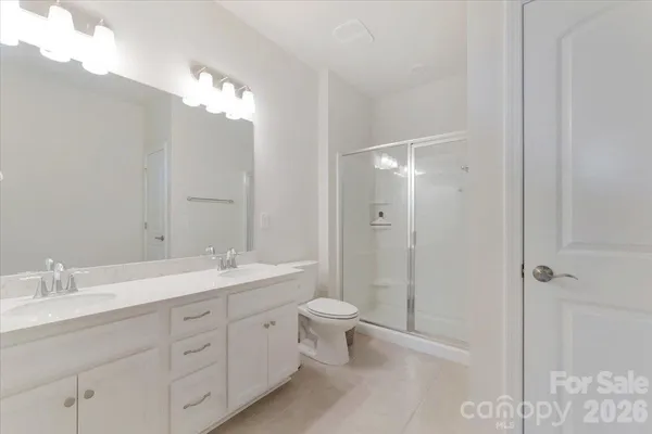 a bathroom with a double vanity sink toilet mirror and shower