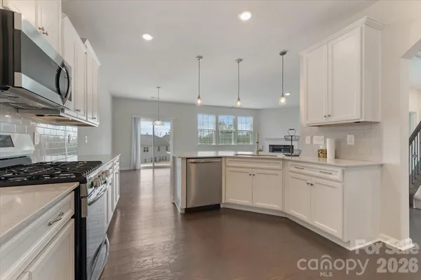 a kitchen with granite countertop a stove top oven a sink a counter space and cabinets