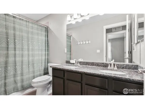 a bathroom with a sink a toilet a mirror and shower curtain