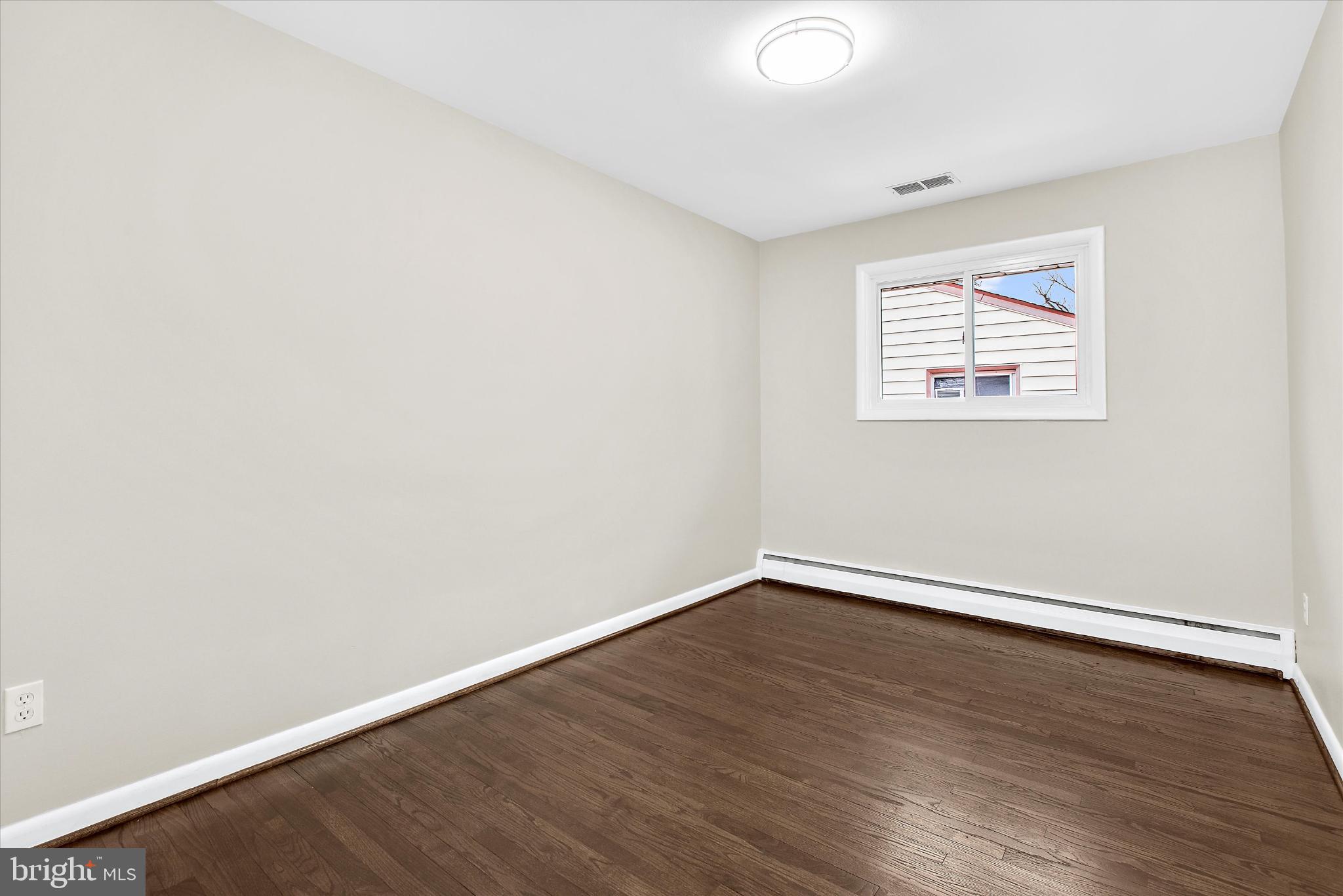 8421 Spring Road Pasadena, MD 21122 - Photo 13 of 30 an empty room with wooden floor and windows
