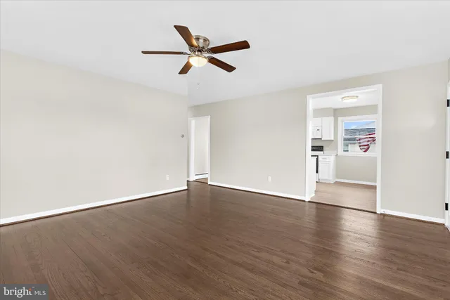 an empty room with wooden floor a ceiling fan and windows