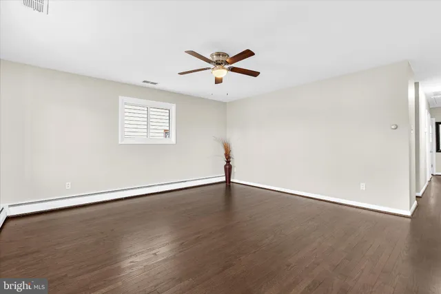 an empty room with wooden floor fan and windows
