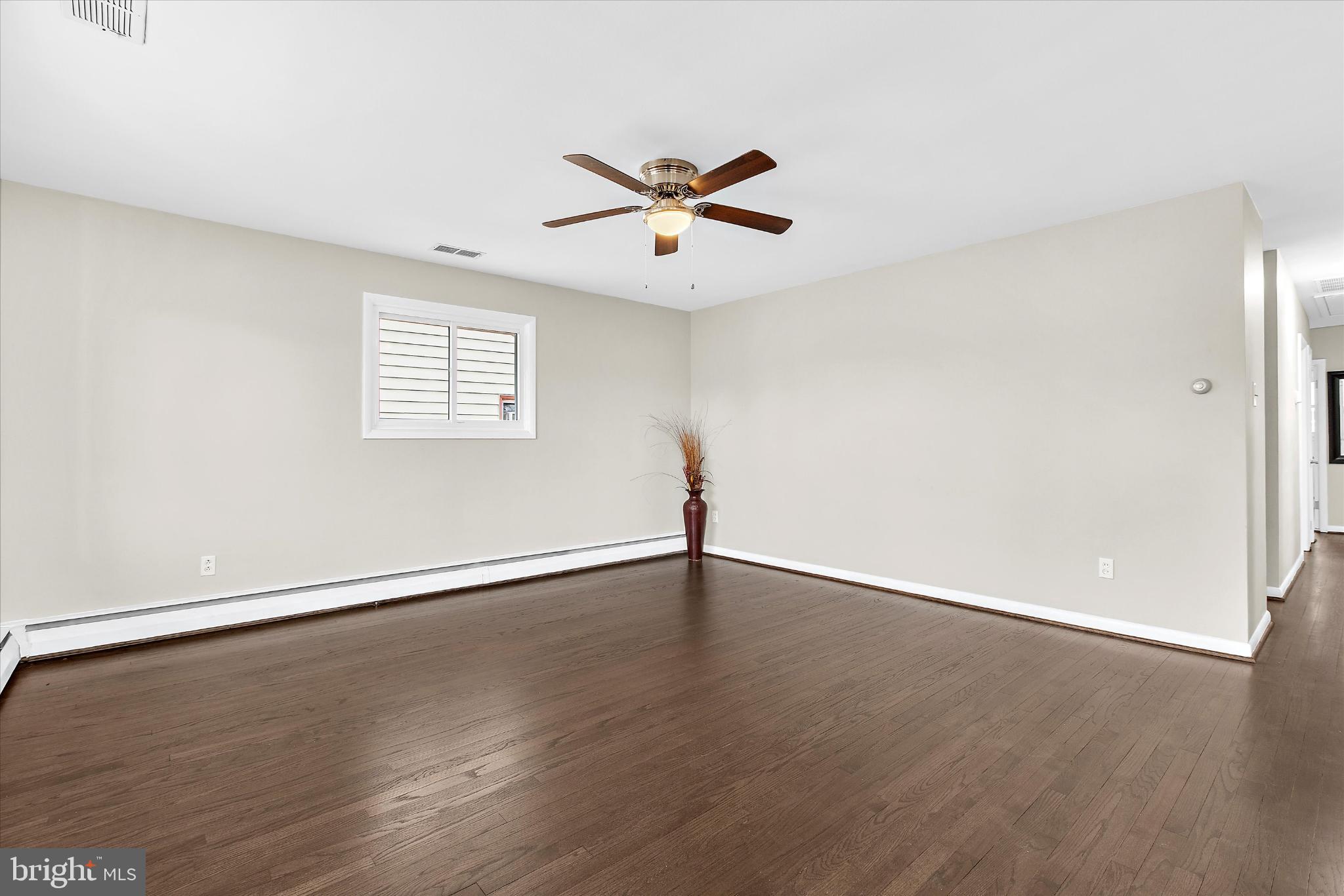 8421 Spring Road Pasadena, MD 21122 - Photo 5 of 30 an empty room with wooden floor fan and windows