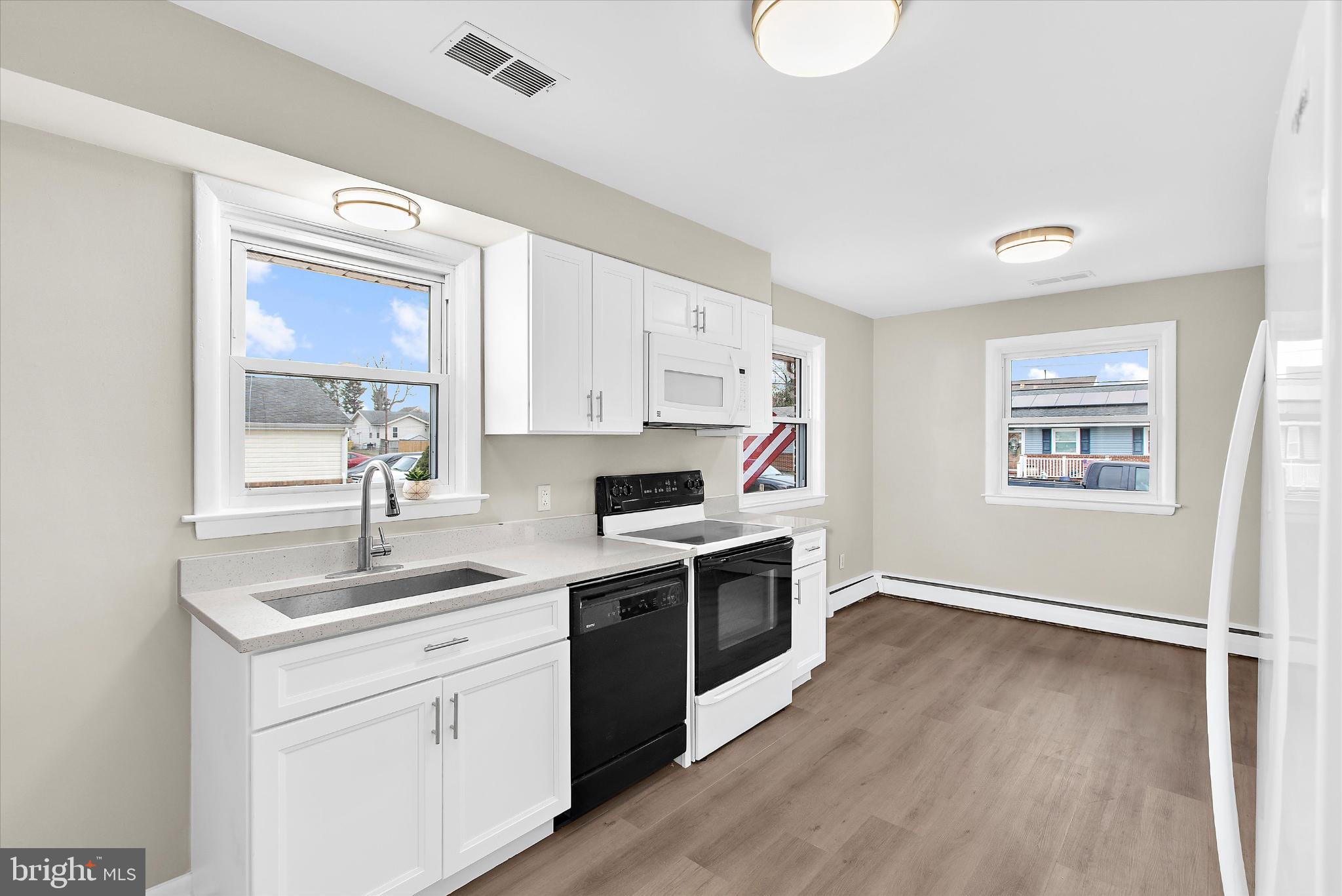 8421 Spring Road Pasadena, MD 21122 - Photo 7 of 30 a kitchen with a sink cabinets stainless steel appliances and a window