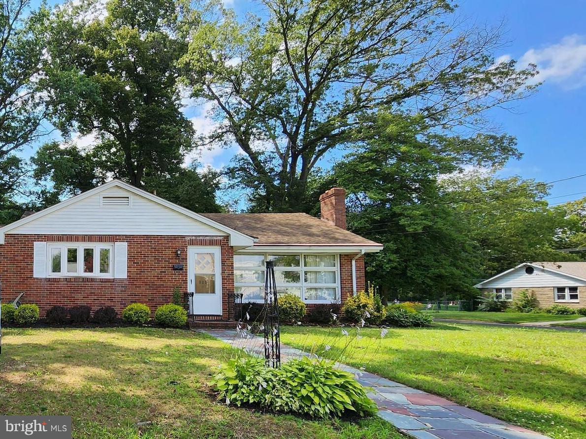 a front view of a house with a garden and trees